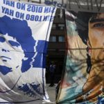 Flags depicting Argentine former football star and coach of Gimnasia y Esgrima La Plata Diego Maradona, hang outside the Ipensa clinic where Maradona has been admitted, in La Plata, Buenos Aires province, on November 3, 2020. - Argentine football great Diego Maradona was admitted to hospital Monday for medical checks, his personal doctor announced. (Photo by JUAN MABROMATA / AFP)
